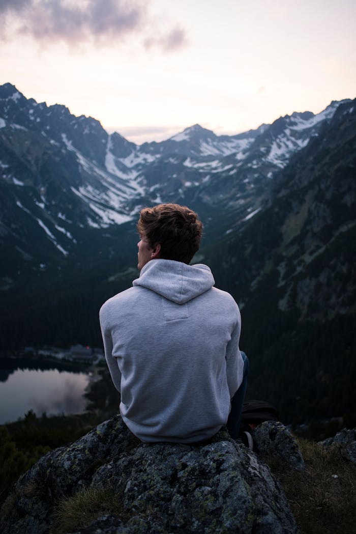 A person enjoying a serene mountain view at twilight, embracing solitude and adventure.